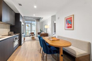 A modern kitchen with dark cabinets, a wooden dining table, and blue chairs.