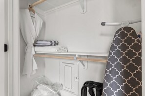 Ein ordentlich eingerichteter Kleiderschrank mit hängender Kleidung, einem Regal mit gefalteten Teilen und einem Stauraum mit Bedienfeld.