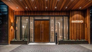 A hotel entrance with a wooden facade, a large glass door, and the name 'NATIVO' illuminated on the wall. - Austin Lux Suite | Downtown Views + Prime Location! (Austin)