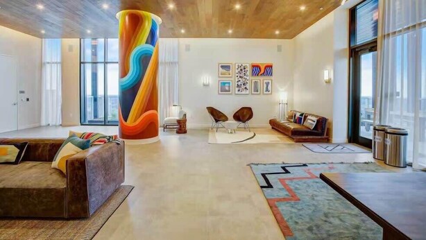 A spacious lobby with a large, colorful cylindrical sculpture, modern seating, and artwork on the walls. - Austin Lux Suite | Downtown Views + Prime Location! (Austin)