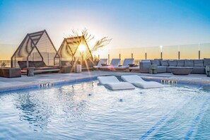 A rooftop pool with lounge chairs and a sunshade structure. - Modern Downtown Condo | Luxury Stay & Steps From Local Hot Spots! (Austin)