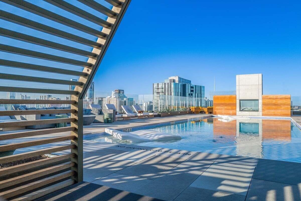 Ein Pool auf dem Dach mit blauem Himmel, moderner Architektur und Liegestühlen.