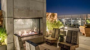 Un área de estar al aire libre moderna con una chimenea y vistas a la ciudad.