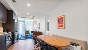 Una cocina moderna con armarios oscuros, una mesa de comedor de madera y un sofá con una manta.