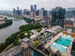 Ein Hochhaus mit Pool auf dem Dach, im Hintergrund ein Fluss und eine Stadtlandschaft.