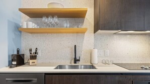 Eine moderne Küche mit Spüle aus Edelstahl, Holzregalen und einem Messerblock.