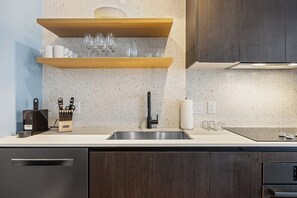 Eine moderne Küche mit Spüle aus Edelstahl, Holzregalen und einem Messerblock.