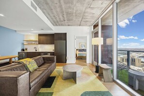 Ein modernes Apartment mit Wohnzimmer, Küche und einem Balkon mit Blick auf die Stadt.