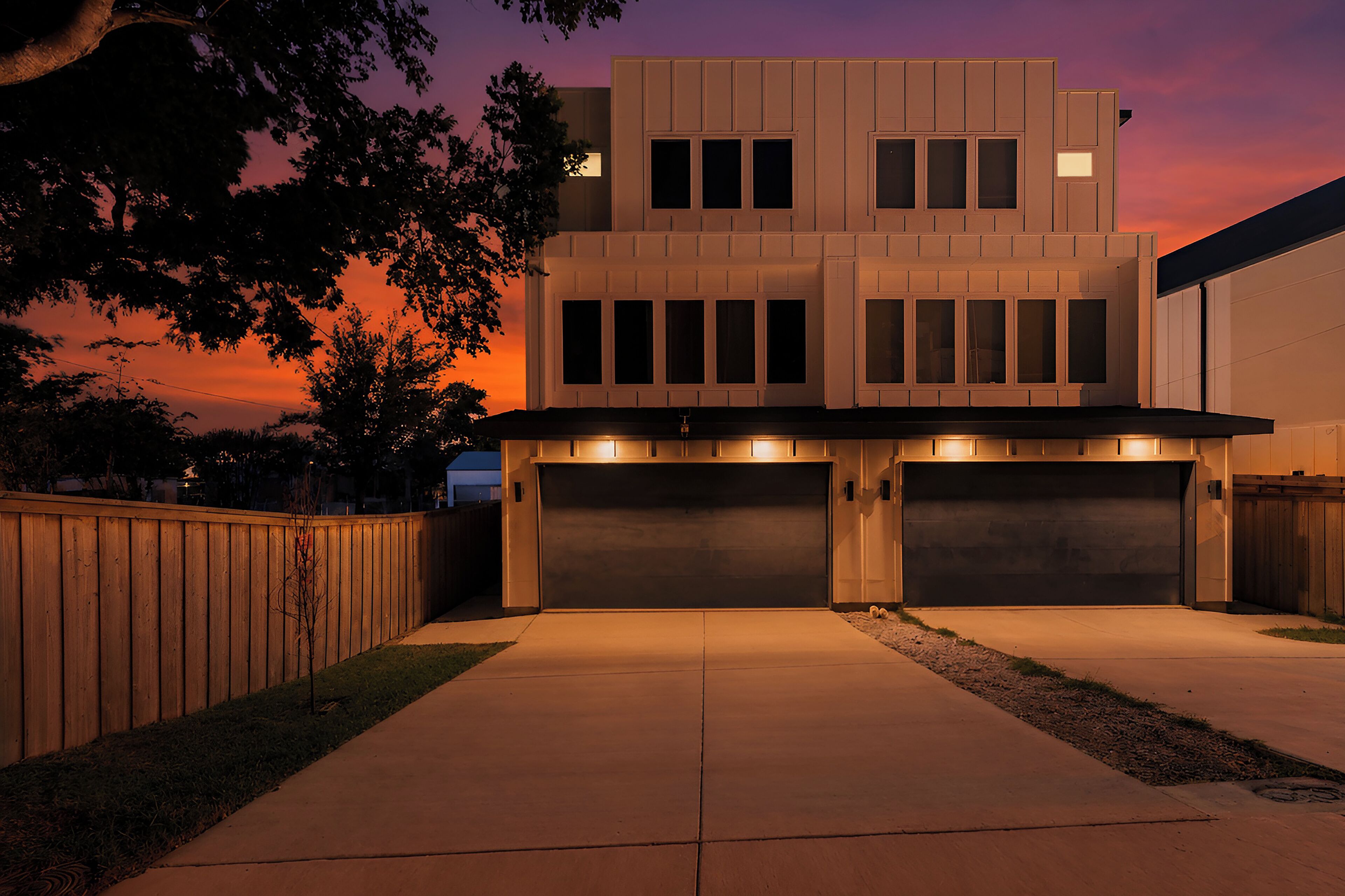 Une maison moderne à deux étages, dotée d’un garage et d’une allée.