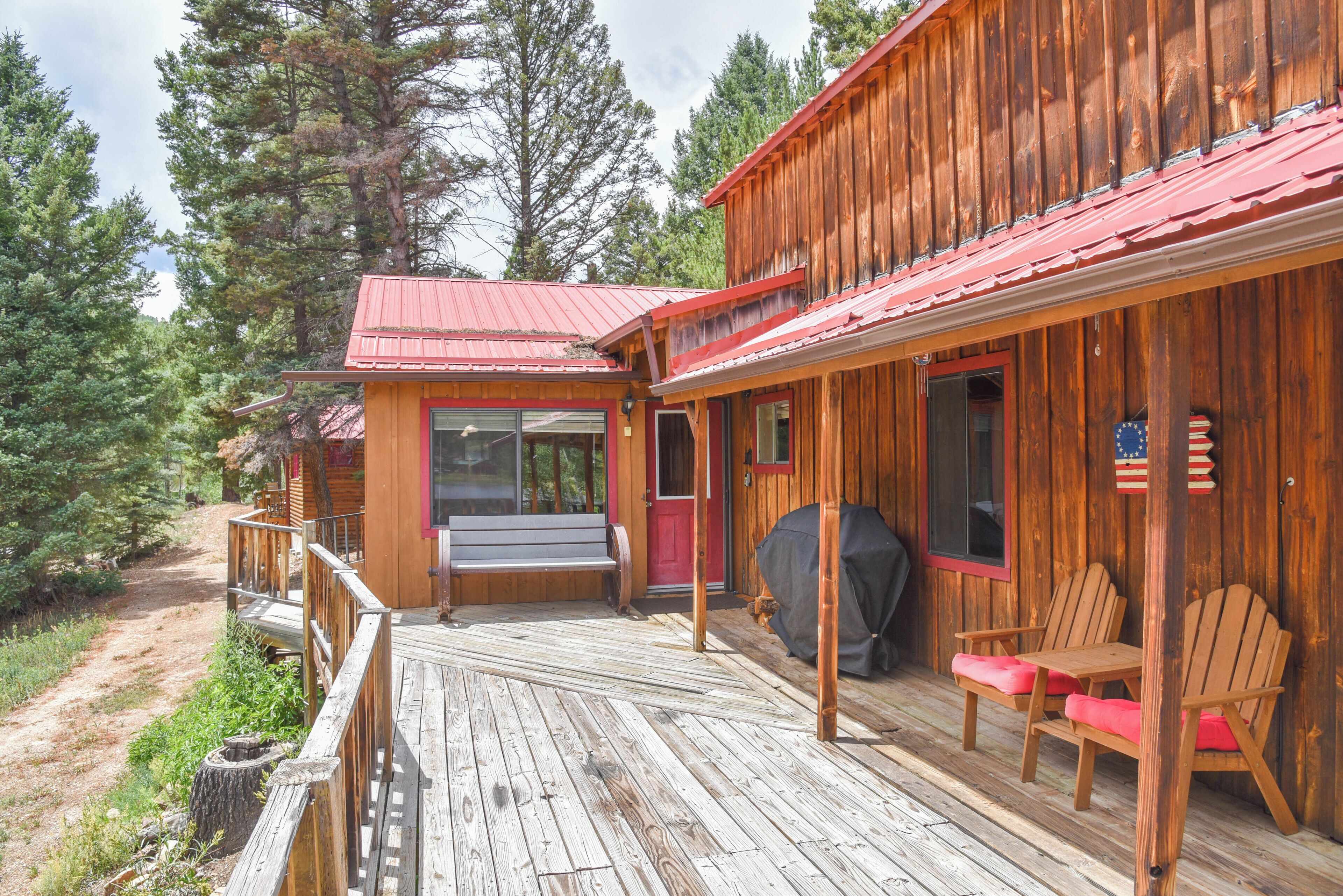 Eine Holzhütte mit Veranda, Bank und Grill.