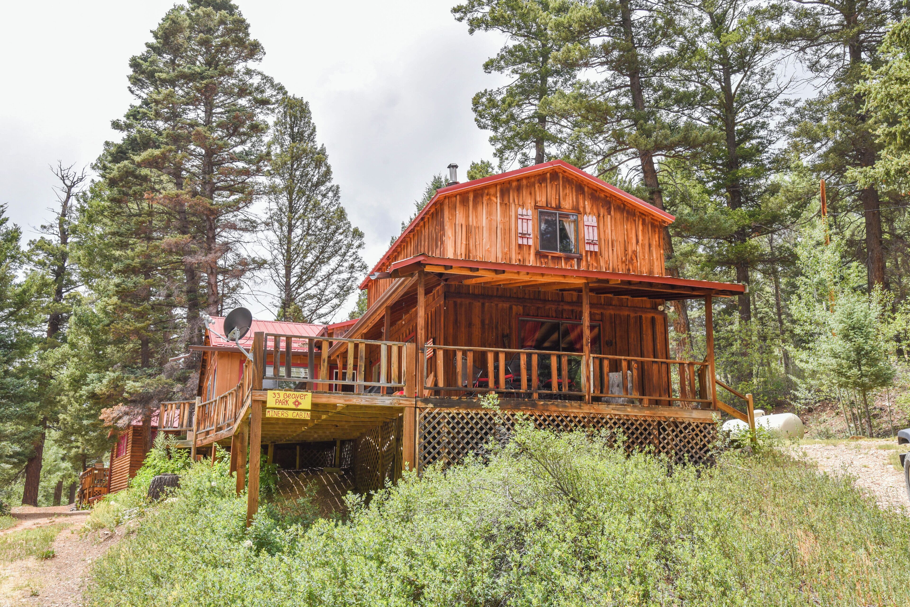 Une cabane en bois dotée d’un balcon, entourée d’arbres.