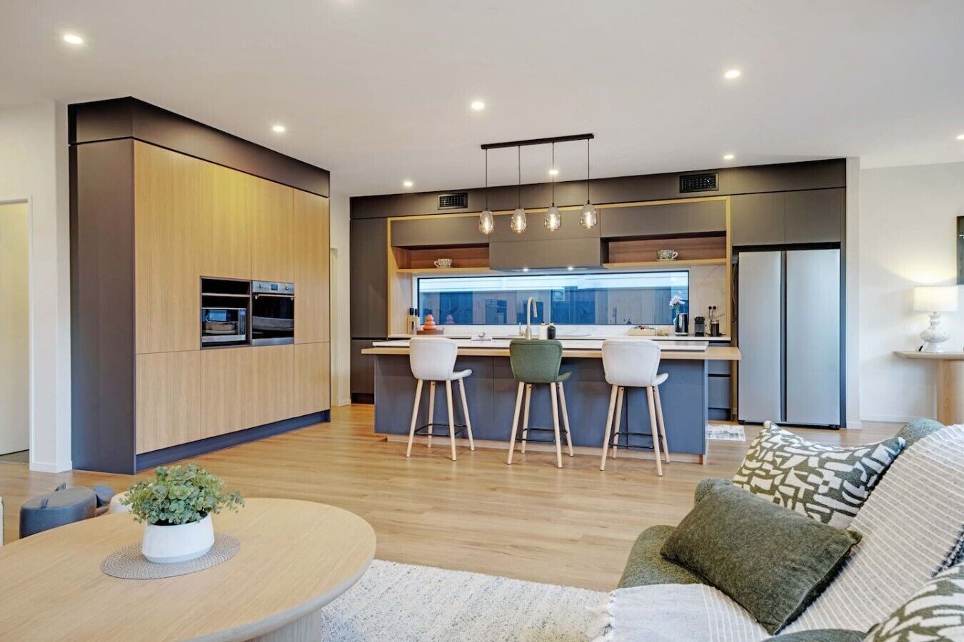 A modern kitchen with a central island, built-in appliances, and pendant lighting.