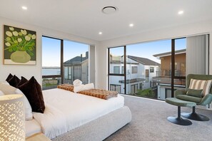 Ein modernes Hotelzimmer mit einem großen Bett, Meerblick und einem Balkon mit einem Sessel.