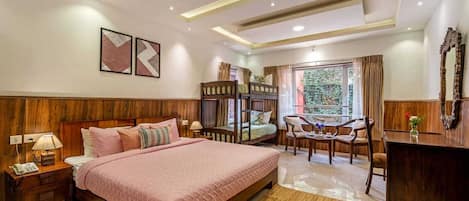 Habitación de hotel con una cama grande, un escritorio, una silla, un ventanal con cortinas y una cama literera.