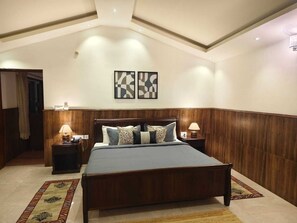 Un dormitorio con una cama de madera, dos mesitas de noche, una lámpara de techo y dos obras de arte abstractas colgadas en la pared.