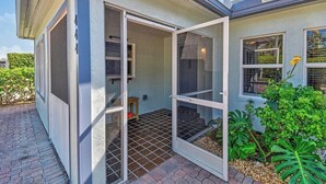 A house with a sliding glass door leading to a patio area. - Best Location! Charming 1-Bedroom House Just Steps from Juno Beach (Juno Beach)