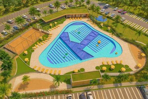 Una amplia piscina con varias pistas, rodeada de tumbonas y una cancha de tenis.