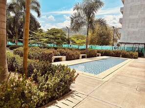 A swimming pool surrounded by lush greenery and palm trees, with a clear sky above. - Year Round Summer Pools and Water Slides Santa Fe (Santa Fe de Antioquia)