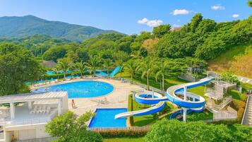 A resort with multiple swimming pools, a water slide, and lush greenery.