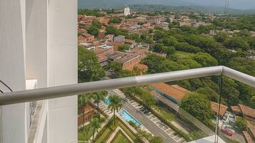 A balcony with a view of a cityscape, including buildings and greenery.