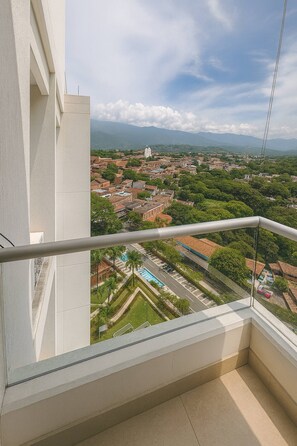 Un balcón con vistas a un paisaje urbano, con edificios y zonas verdes.