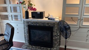 Ein Zimmer mit Kamin, Ventilator und einer Blumenvase.