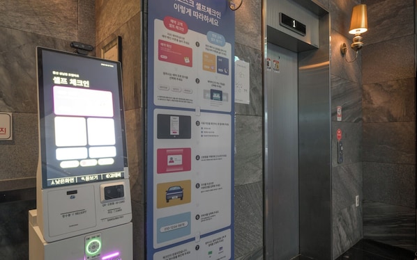 Un quiosco digital informativo con instrucciones para usar un ascensor, un lector de tarjetas Samsung Pay y un escáner de código QR.