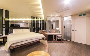 Una habitación de hotel moderna con una cama grande, un tocador con espejo, un escritorio y un vestidor.