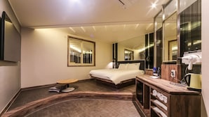 A hotel room with a bed, a round wooden table, a mirror, a vanity with a hairdryer, and a shelf with towels. - Ulsan Seongnam Hotel Mar (Ulsan)