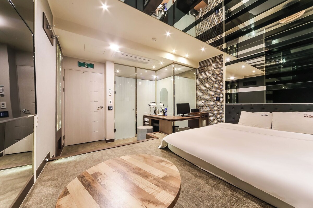 Una habitación de hotel moderna con una cama grande, un escritorio, un espejo y una pared con un diseño decorativo.