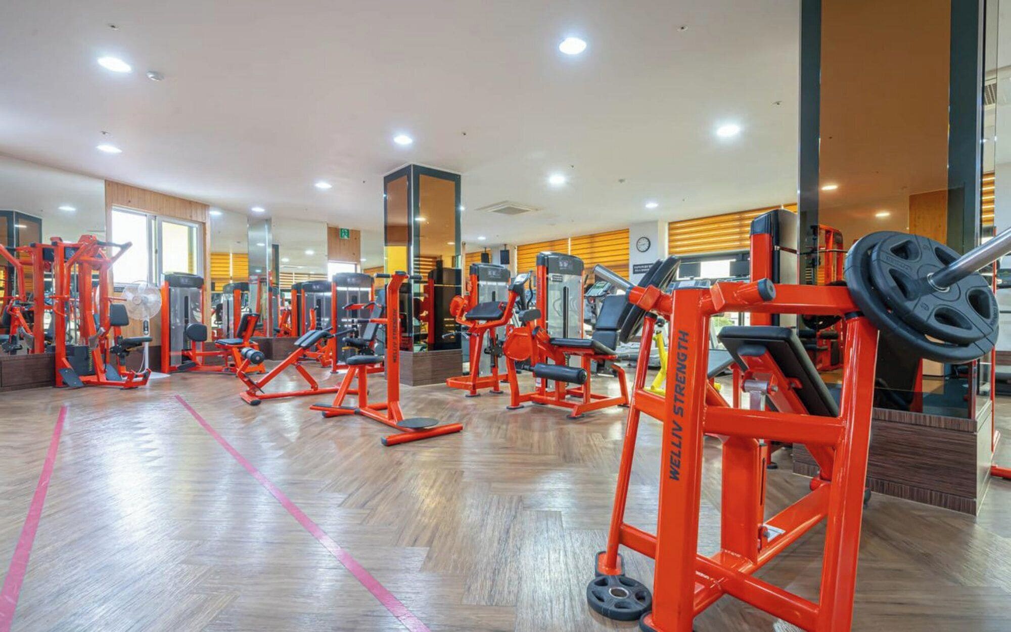 Un gimnasio con diversas máquinas de ejercicio, una banca de pesas y un espejo.