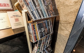 Un estante con varios DVDs, un código QR y un cartel con texto coreano.