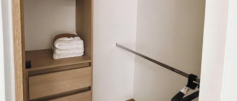 Un vestidor con estantes de madera, barra para colgar ropa y una caja de almacenamiento.