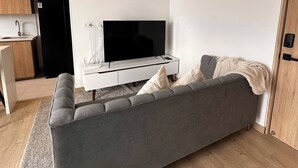 A modern living room with a grey sofa, a flat-screen TV, a ceiling fan, and a wooden floor. - Epic View 25 Pablo Tobón Cardiovascular (Medellín)