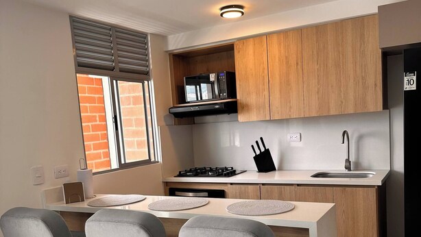 A modern kitchen with a central island, a built-in oven, and a black refrigerator. - Epic View 25 Pablo Tobón Cardiovascular (Medellín)