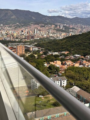 A cityscape with a mix of residential and high-rise buildings, a prominent hill in the background, and a clear sky. - Epic View 25 Pablo Tobón Cardiovascular (Medellín)