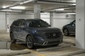 Een parkeergarage met betonnen pilaren, een auto en een brandblusser.