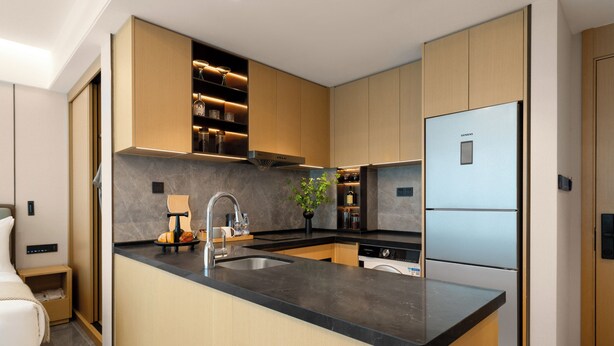 A modern kitchen with a central island, built-in appliances, and a minimalist design. - LN Residence suites (Guangzhou)