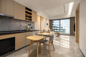 A modern kitchen with a dining area, a large window with a view of a cruise ship, and a flat-screen TV. - LN Residence suites (Guangzhou)