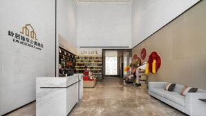 A hotel lobby with a reception desk, a sofa, a bookshelf, and a sign reading 'LN LIFE.' - LN Residence suites (Guangzhou)