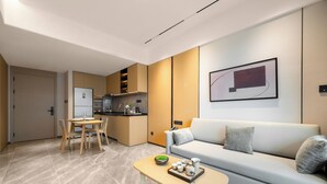 A modern living room with a sofa, a dining table, and a kitchen area in the background. - LN Residence suites (Guangzhou)