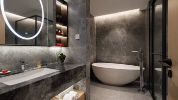 Een moderne badkamer met een ruime wastafel, een vrijstaand bad en een douche met glazen wanden.
