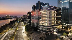 A multi-story hotel with a modern glass facade, located adjacent to a river with a bridge in the background. - LN Residence suites (Guangzhou)