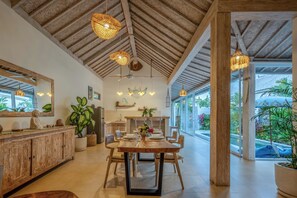 A spacious dining area with a wooden table and chairs, a large mirror, and hanging wicker lamps. - 2 BR Villa Bali Pearl Stay Between Dream and Reality in Seminyak (Badung)