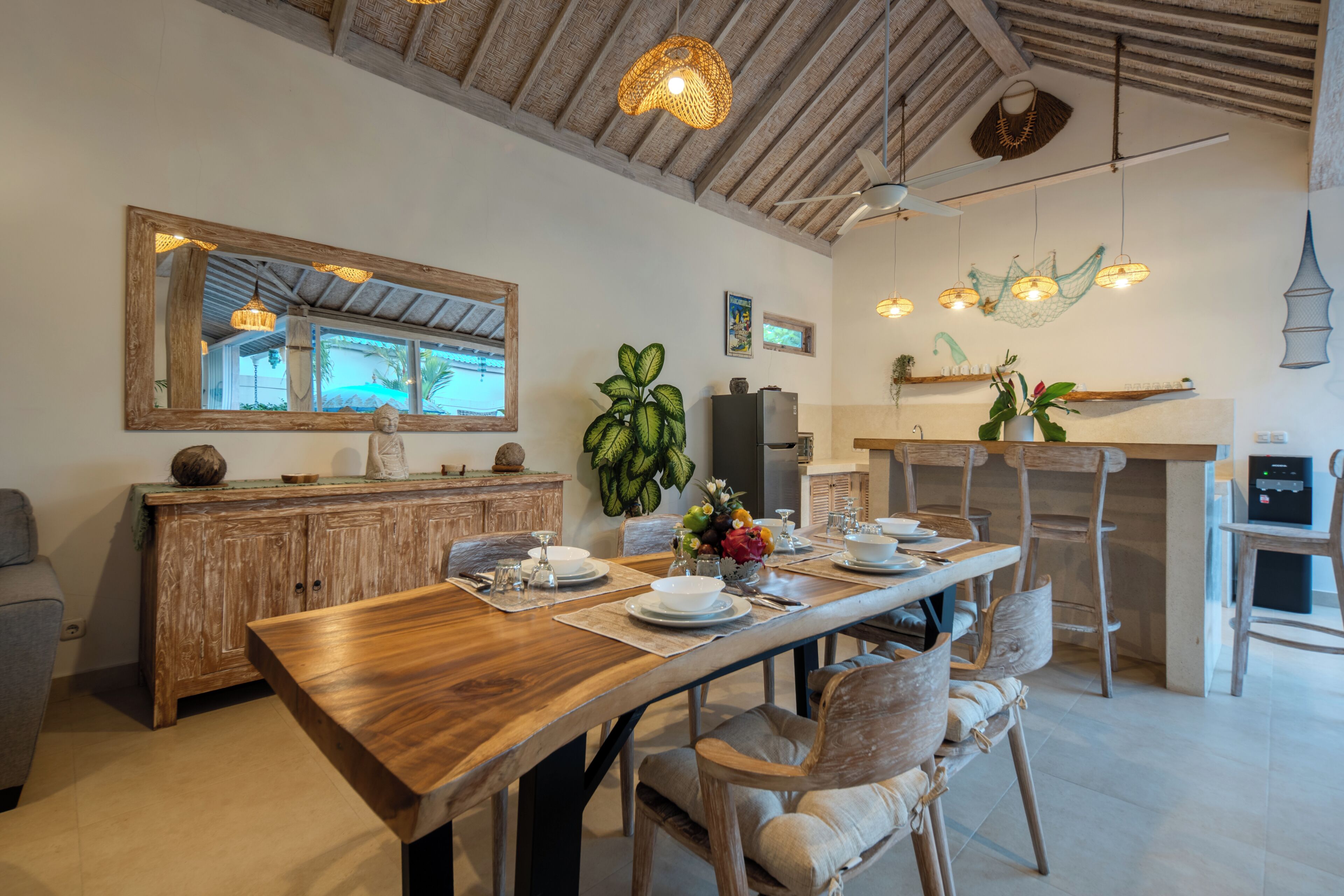 A dining area with a wooden table, chairs, and a large mirror on the wall.