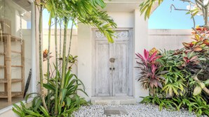 Un patio con puerta de madera, plantas en macetas y un camino de piedra.