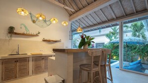 Cocina con armarios de madera, un lavamanos y una barra con taburetes.