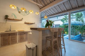 A kitchen with wooden cabinets, a sink, and a bar area with stools. - 2 BR Villa Bali Pearl Stay Between Dream and Reality in Seminyak (Badung)