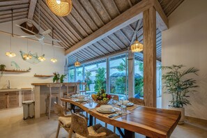 A dining area with a wooden table, chairs, and a view of greenery outside. - 2 BR Villa Bali Pearl Stay Between Dream and Reality in Seminyak (Badung)