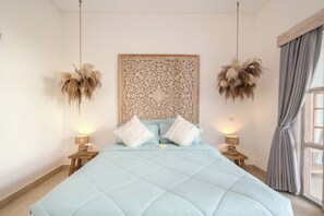 A bedroom with a large bed, two bedside tables, a decorative headboard, and a window with curtains. - 2 BR Villa Bali Pearl Stay Between Dream and Reality in Seminyak (Badung)